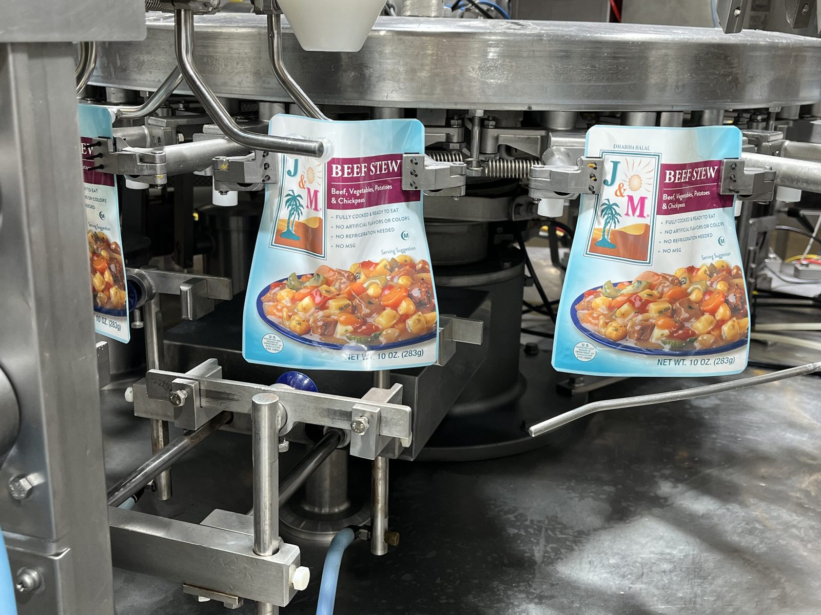J&M Beef Stew pouches moving through a filling machine on a production line